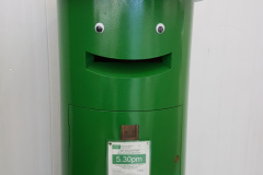 Green post box with eyes stuck above the envelope hole to make it look as if it's smiling