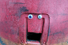 close up of section on a road traffic cone with eyes stuck on it so it looks like a cheery face.